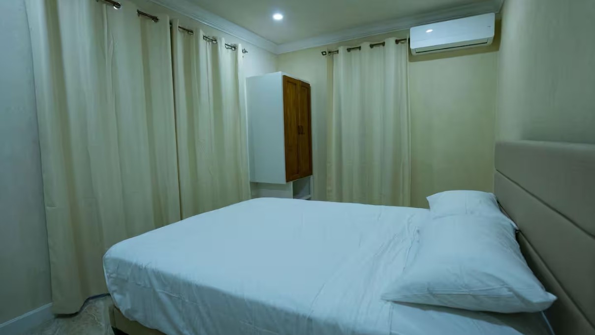 Bedroom with queen bed and cream curtains