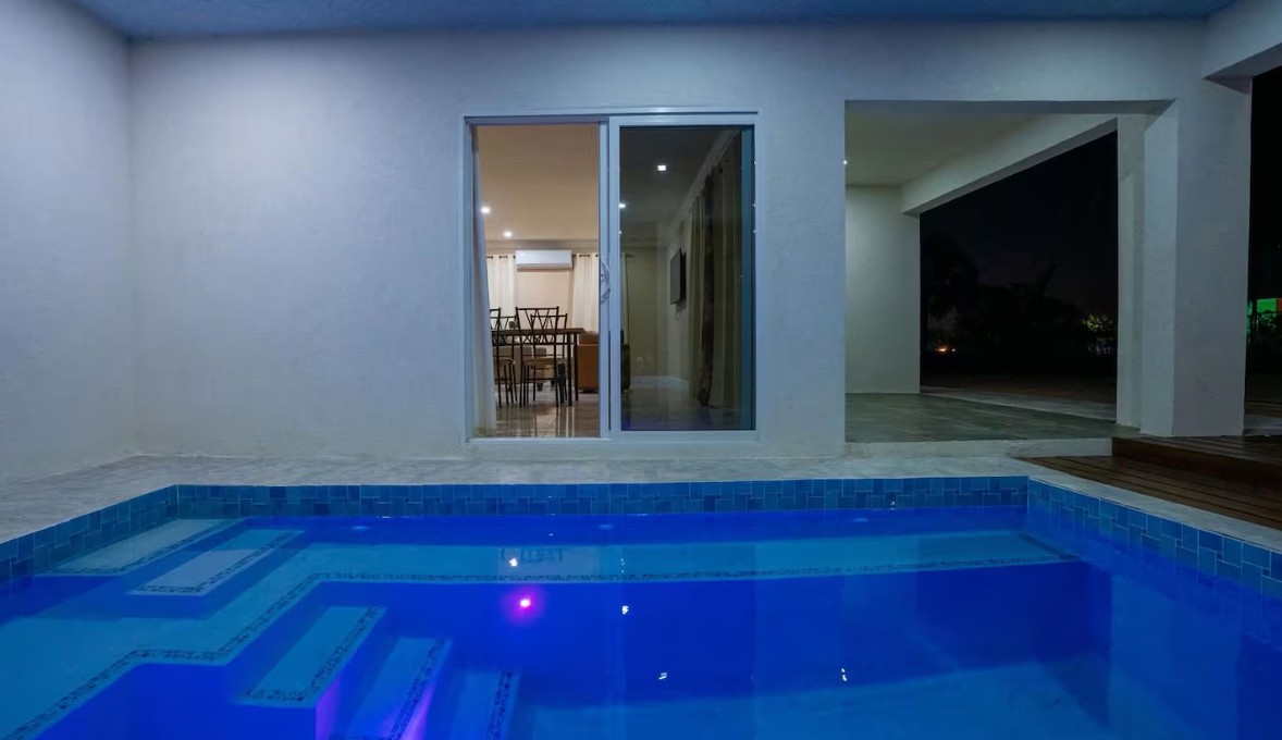 Private pool lit blue at night beside the villa